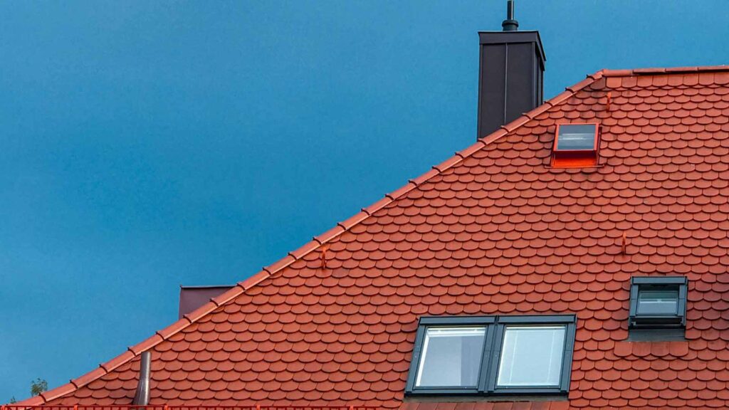 A beautiful unfinished copper roof from an unknown location, picture taken from Unsplash. Blu sky and black chimney.